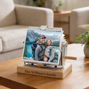 Puede incluir: Un expositor de fotos giratorio con base de madera, con una foto familiar. La pantalla tiene un marco plateado y un asa de madera. La base está grabada con "The William's family". Las fotos muestran una familia de cuatro.