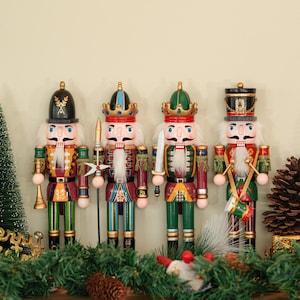 Op de afbeelding: Vier kleurrijke houten notenkrakers met gedetailleerde uniformen en hoeden. Elke figuur heeft een witte baard en snor en houdt een ander accessoire vast, waaronder een speer, zwaard en trommel. Een feestelijke kerstversiering.