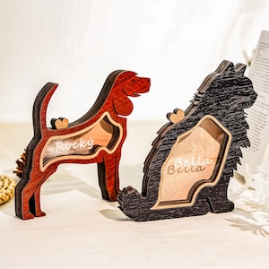 May include: Two wooden pet-themed decorative frames. One is a red dog-shaped frame with the name "Rocky" and a heart. The other is a black cat-shaped frame with the name "Bella" and a heart. Both have a natural wood interior.