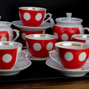 Può includere: Un servizio da tè vintage con tazze, piattini e piatti da portata rossi a pois bianchi. Il set include tazze da tè, piattini, zuccheriera e lattiera. I bordi e le maniglie hanno finiture dorate. Un design classico e affascinante.