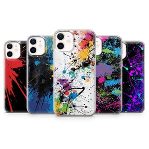 Puede incluir: Una colección de cinco fundas para teléfonos inteligentes con diseños de salpicaduras de pintura coloridas. Las fundas presentan una variedad de colores, incluyendo rojo, azul, amarillo, verde, morado y negro, creando un aspecto vibrante y artístico. Cada funda tiene un borde transparente.