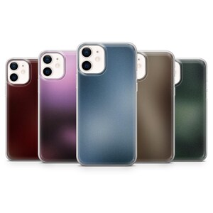 May include: Five mobile phone cases in a row, each in a different colour. The cases are in burgundy, purple, blue, brown, and green. Each has a clear border and a dual-lens camera cutout.