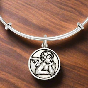 May include: Silver charm bracelet with a silver angel charm. The bracelet has three charms attached to it, one with the text "Made with Energy Technology", one with the text "Made with Love", and one with the text "Trade Australia".