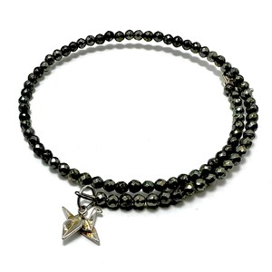 May include: A black beaded bracelet with a silver origami crane charm. The bracelet is made of small, faceted beads and is double-wrapped.