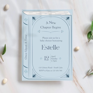 Peut inclure: Une invitation de baby shower bleu clair en forme de livre. Le texte dit « Un nouveau chapitre commence » et invite les invités à honorer Estelle. La date est le 12 avril, dimanche, de 14h à 17h. L'invitation comprend une adresse et les coordonnées RSVP.