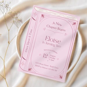 Peut inclure: Une carte d'invitation rectangulaire rose pâle conçue pour ressembler à une couverture de livre. Le texte indique A New Chapter Begins, Eloïse Is Turning Two, Once Upon A Time, avec les détails de l'événement le 12 août, dimanche, 14h-16h.