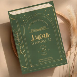 Può includere: Un biglietto d'invito di compleanno rettangolare verde con illustrazioni dorate di un libro, stelle e un arco. Il testo recita: Another page in the book, Lucas is turning 32, October 28, 2-4 pm Sunday, 123 Books Street, Join us to celebrate!