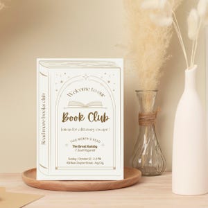 Puede incluir: Una invitaci&oacute;n crema para un club de lectura con el texto "Welcome to our Book Club" y "The Great Gatsby". La invitaci&oacute;n est&aacute; dise&ntilde;ada para parecerse a un libro y est&aacute; sobre una bandeja de madera. Un jarr&oacute;n con flores secas y un jarr&oacute;n blanco est&aacute;n en el fondo.