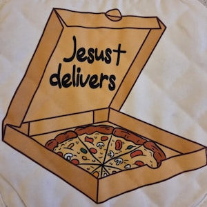 May include: A pizza box with the words "Jesust delivers" printed on the lid. Inside the box is a pizza cut into eight slices, with toppings including mushrooms and tomatoes. The box is brown and the pizza has a golden crust.
