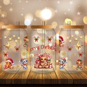 Op de afbeelding: Drie glazen potten met houten deksels, versierd met kerstillustraties. Elke pot heeft peperkoekenmannetjes, sneeuwmannen, zuurstokken en de tekst "Merry Christmas". De potten staan op een houten oppervlak.