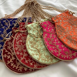 May include: A collection of colorful, embroidered drawstring pouches. The pouches are in shades of peach, navy, burgundy, light green, hot pink, and orange. Each pouch features gold floral embroidery and a beaded drawstring closure.