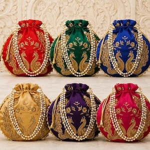 May include: Six round drawstring pouches in red, green, blue, gold, purple, and pink satin. Each pouch features gold metallic embroidery of two facing peacocks and floral motifs, finished with a white faux pearl beaded handle and gold tassels.