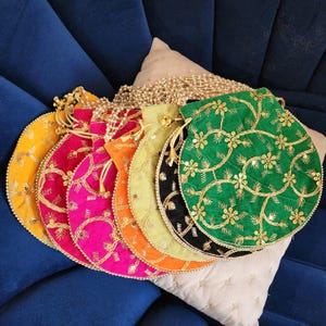 May include: A collection of six circular drawstring pouches in yellow, magenta, orange, light green, black, and green. Each pouch features gold metallic embroidery in a floral vine pattern with sequins and a pearl-beaded drawstring closure.