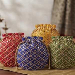 May include: Four round drawstring pouches in red, blue, green, and yellow. Each pouch features a gold lattice pattern with small circular mirrors embedded at the intersections. The bags have a gathered top closure with matching gold drawstring cords.
