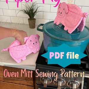 May include: A pink pig-shaped oven mitt with a swirling pattern, featuring black embroidered eyes and nostrils. The text Piper Pig and Oven Mitt Sewing Pattern PDF file is visible. The mitt is shown next to a teal Dutch oven on a stove.