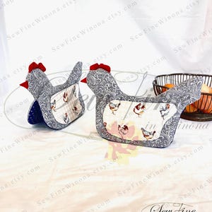 May include: Two chicken-shaped oven mitts. The mitts are gray with a white and gray floral pattern. The front of the mitts have a white background with chicken illustrations. The chickens have red combs and beaks. The mitts have red bows on top.