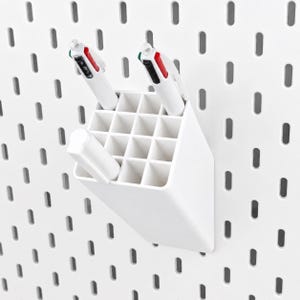 May include: A white plastic organizer with a grid of square compartments mounted on a white pegboard. Two multi-color ink pens with white barrels and one white marker are inserted into the slots of the rectangular storage container.