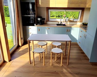 May include: A modern kitchen with light blue cabinets, wooden countertops, and a white table with four small stools. The room has large windows and a built-in oven. The floor is made of wood.