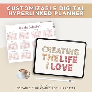 Op de afbeelding: Een digitale planner met een jaarkalender met roze roosters en een tabletscherm met de tekst CREATING THE LIFE I LOVE in glitterende gouden en roze letters, vergezeld van een witte koffiekop en een digitale styluspen.