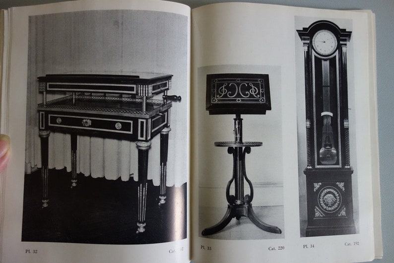 Puede incluir: Imagen en blanco y negro de muebles antiguos. Incluye una mesa con cajones, un atril y un reloj de pie. La mesa tiene patas decorativas y un tirador. El reloj tiene un p&eacute;ndulo y una esfera redonda.