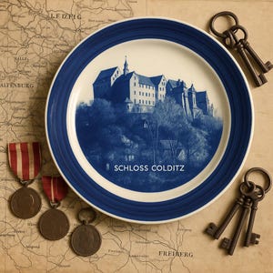 May include: A decorative plate with a blue and white rim features a blue and white image of Schloss Colditz castle. The plate is surrounded by antique keys and medals, set against a vintage map background.