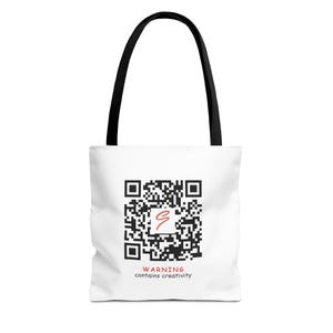 Op de afbeelding: Witte tote bag met zwarte handvatten. De tas heeft een zwart-witte QR-code met een rode kronkel in het midden. De tekst onder de QR-code luidt "WAARSCHUWING bevat creativiteit."