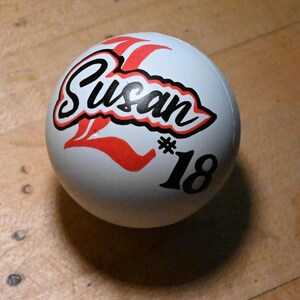 Pu&ograve; includere: Una palla sferica bianca con un design grafico personalizzato. Il nome Susan &egrave; stampato in corsivo nero con un bordo rosso, posizionato sopra una grande lettera L rossa e il testo nero #18. La superficie della palla &egrave; liscia e opaca.