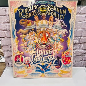 Peut inclure: Une affiche de cirque vintage Ringling Bros. et Barnum & Bailey. L'affiche présente un tigre, des artistes de cirque et divers animaux. Le texte "The Living Carousel" est bien en évidence, avec le logo Feld Entertainment en haut.