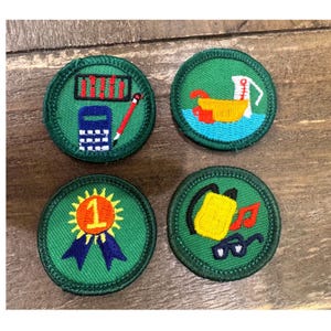May include: Four circular embroidered patches with green borders. One features a calculator and pencil, another a yellow bowl with a white pitcher on blue water, one a gold number one ribbon, and the last a yellow backpack, red music note, and glasses.