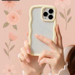 May include: A white phone case with a wavy, cream-coloured border. The case has a clear back and a camera cutout with three black lenses.