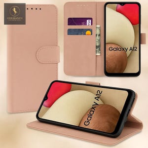 May include: A pale pink leather phone case with a magnetic clasp, card slots, and a phone screen displaying "Galaxy A12." The case is open, revealing the phone and the interior design. The brand logo is visible in the upper left corner.