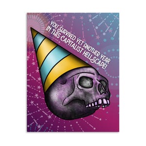 May include: A greeting card featuring a purple skull wearing a party hat with yellow and blue stripes. The card has the text "YOU SURVIVED YET ANOTHER YEAR IN THIS CAPITALIST HELLSCAPE!" against a pink and purple background with starbursts.