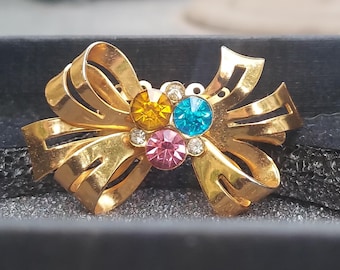 Spilla vintage Coro a forma di fiocco dorato con strass multicolore.