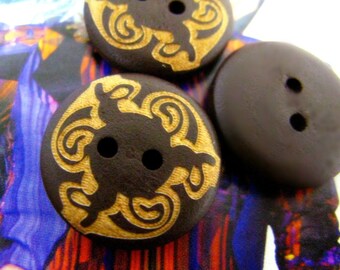 May include: Three brown wooden buttons with two holes each. Two buttons have a gold swirl design and one button is plain.