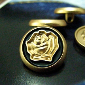 Peut inclure: Boutons dorés avec un fond noir et un motif de rose dorée en relief.