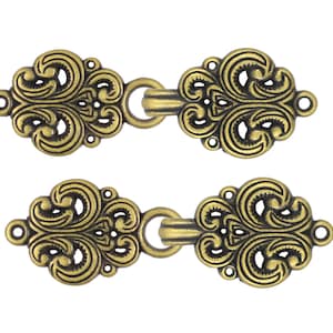 May include: Two antique gold-toned metal clasps with intricate floral designs. Each clasp has a loop on one end and a hook on the other.
