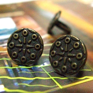 May include: Two antique bronze metal buttons with a decorative design of a starburst with eight points and eight circles around the starburst.