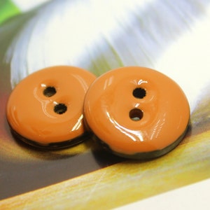 May include: Two orange buttons with black trim and two holes each.