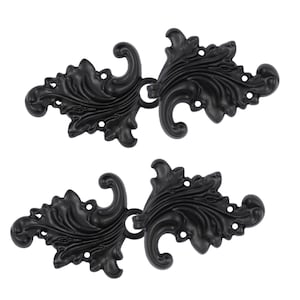 Pode incluir: Dois fechos decorativos de metal preto com design floral. Cada fecho tem um laço no centro para prender ao tecido.