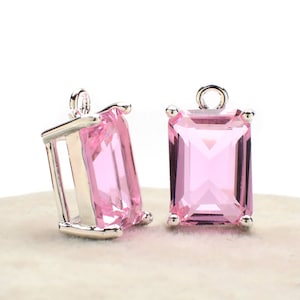 Puede incluir: Dos colgantes de plata con piedras de cristal de forma esmeralda rosa. Los colgantes tienen un bucle en la parte superior para sujetarlos a un collar o pulsera.