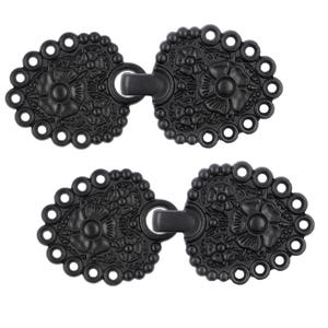 May include: Two black metal decorative clasps with a floral design. Each clasp has a loop on the side and a hook on the other side.