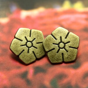 Puede incluir: Dos botones de metal de color dorado antiguo en forma de flor con un diseño en relieve.