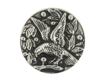 May include: Silver-toned metal button featuring a detailed design of a bird in flight with its wings spread wide. The bird is surrounded by stylized leaves and berries.