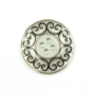 Puede incluir: Un botón blanco con un vástago de cuatro agujeros y un diseño de espiral negro.