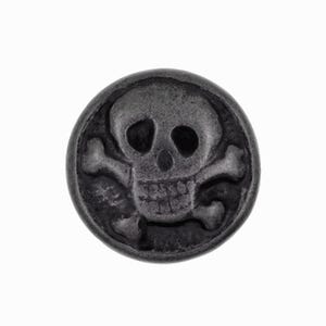 Pode incluir: Um botão redondo cinza escuro com um desenho de caveira e ossos cruzados. A caveira tem cavidades oculares, uma cavidade nasal e dentes. Os ossos cruzados estão posicionados sob a caveira, criando um símbolo pirata clássico.
