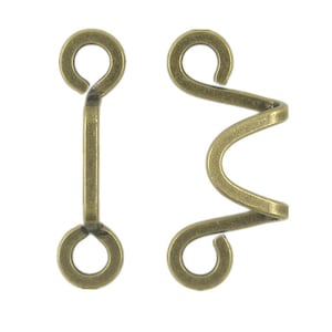 Könnte beinhalten: Ein Paar antike goldfarbene Metallhaken- und Ösenverschlüsse. Der Haken ist eine einfache Schlaufe, und die Öse ist eine gedrehte, dekorative Schlaufe.