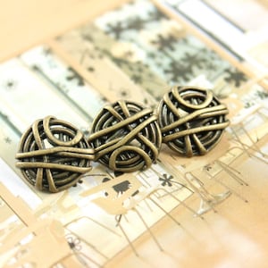 Puede incluir: Tres botones de metal de color dorado con un diseño tejido. Los botones están dispuestos en una fila sobre un fondo estampado.