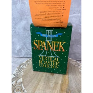 May include: A green rectangular box for the Spanek Vertical Roaster Collection with white polka dots. The front features the text THE ORIGINAL SPANEK VERTICAL ROASTER COLLECTION. An orange insert extends from the top with printed product details.