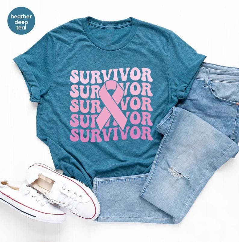 May include: A teal t-shirt with the word "SURVIVOR" in pink, stacked vertically with a pink ribbon graphic. Light blue jeans and white sneakers complete the casual ensemble. The shirt is a heather deep teal color.