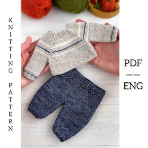 Könnte beinhalten: Ein Miniatur-Strick-Outfit, bestehend aus einem grauen Pullover mit blauen und weißen Streifen und einer blauen Hose. Der Pullover hat lange Ärmel und die Hose hat zwei kleine Knöpfe. Der Text "KNITTING PATTERN PDF -- ENG" ist sichtbar.